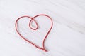 Red thread in the shape of heart on white wooden background. Easter sign. Valentine's Day sign. Love sign Royalty Free Stock Photo