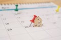 red thumbtack with miniature wooden house on calendar