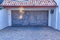 Red tile roof overhang above the wooden door of attached garage of a house