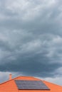 Red tile roof with photovoltaic panels during stormy weather Solar PV installation and dark blue sky Royalty Free Stock Photo