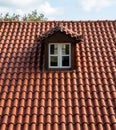 Red tiled roof with attic. Dormer window white color on garret, rooftop