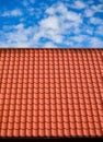 Red tiled roof. CLouds in blue sky. Close-up.
