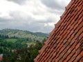 Red tiles roof, clouds and green landscape on the background