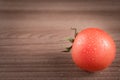 Red tomato with drops of water on wooden bckground