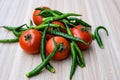 Red tomato and green chili pepper on plain wooden table, green essential vegetables for all essential foods, view of unpeeled Royalty Free Stock Photo