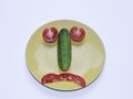 red tomato and green cucumber are laid out in the shape of a sad smiley face Royalty Free Stock Photo