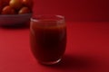 Red tomato juice in a glass next to tomatoes lie on a plate on a red background with a place for text. Healthy Food Drinks Royalty Free Stock Photo