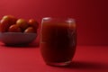 Red tomato juice in a glass next to tomatoes lie on a plate on a red background with a place for text. Healthy Food Drinks Royalty Free Stock Photo
