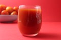 Red tomato juice in a glass next to tomatoes lie on a plate on a red background with a place for text. Healthy Food Drinks Royalty Free Stock Photo