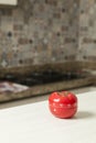 Red tomato-shaped kitchen timer with cooking in the background. Royalty Free Stock Photo