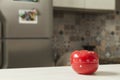 Red tomato-shaped kitchen timer with cooking in the background. Royalty Free Stock Photo