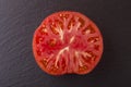 Red tomato slice in black background, top view, closeup, macro Royalty Free Stock Photo