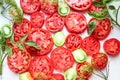 Red tomato slices with green ones on a gray background with dill branches, close-up, top view