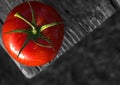 Red tomato with water drops on grey barn board