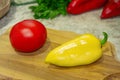 Red tomato, yellow bell pepper on a wooden board. Parsley, cilantro and two red peppers in the back Royalty Free Stock Photo