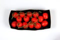 Red tomatoes in a black cardboard box on a white background Royalty Free Stock Photo