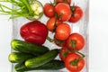 Red tomatoes on a branch, green onions in a glass, one red bell pepper, large cucumbers are shown in close-up from the top view Royalty Free Stock Photo