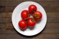 Red tomatoes on branch on white plate on wet wooden table Royalty Free Stock Photo