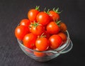Red tomatoes cherry in transparent salad bowl on black Royalty Free Stock Photo