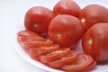 Red tomatoes on a white plate. Sliced tomatoes on a white background. Vegetables on a plate