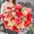 Red tones Beautiful bouquet of mixed flowers in womans hands. the work of the florist at a flower shop. Handsome fresh