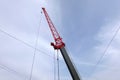 Red top part of big construction crane boom and many pulled metal cables in blue sky Royalty Free Stock Photo