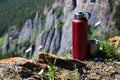 A red tourist thermos with a mug stands on top of the mountain. Royalty Free Stock Photo