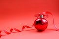 Red toy ball for the Christmas tree with a red ribbon on a red background Royalty Free Stock Photo