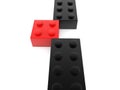 A red toy brick has been pushed out of a row of black toy bricks Royalty Free Stock Photo