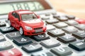 Red toy car on calculator, auto tax and financing, insurance and loans, concept of savings money on vehicle purchase. Royalty Free Stock Photo