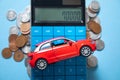 Red toy car, calculator and coins on the blue background Royalty Free Stock Photo