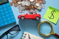 Red toy car, calculator and coins on the blue background Royalty Free Stock Photo