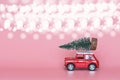 Red toy car with a christmas tree on the roof on pink paper background. Winter delivery, xmas, happy new year 2020 celebration Royalty Free Stock Photo