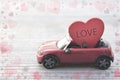 Red toy car delivering heart with word love