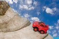 Red toy car driving up a mountain Blue sky with clouds Royalty Free Stock Photo