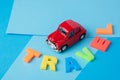 Red toy car and inscription plastic travel letters on a blue background