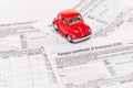 Red toy car on insurance documents on white