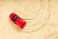 A red toy car stuck in the sand, wheel marks on the sand Royalty Free Stock Photo