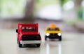 Red toy car truck and yellow old taxi car on road on blurred background, traffic and drive concept Royalty Free Stock Photo