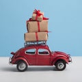 Red toy car Volkswagen Beetle riding with New Year gift on the top