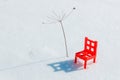 A red toy chair in the snow under a makeshift palm tree. vacation broke