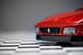 Red toy Ferrari 348TB sports car close up product shot on a chequered ground and gray background Royalty Free Stock Photo