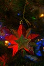 Red toy in the form of a star hangs on a christmas tree with garlands Royalty Free Stock Photo