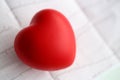 Red toy heart lie on cardiogram chart paper closeup