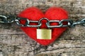 Red toy heart wrapped with a chain and closed with a metal lock. Love concept.