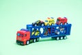 Red toy plastic car transporter with special equipment inside on a green background, toys for boys Royalty Free Stock Photo