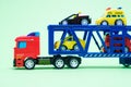 Red toy plastic car transporter with special equipment inside on a green background, toys for boys Royalty Free Stock Photo