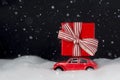 Red toy retro car carries on a roof a Christmas gift on snow Royalty Free Stock Photo