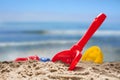 red toy shovel and plastic molds in the sand at the beach, concept of summer vacation with children at sea, copy space Royalty Free Stock Photo