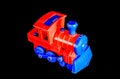 A red toy train with blue wheels sits on a black background Royalty Free Stock Photo